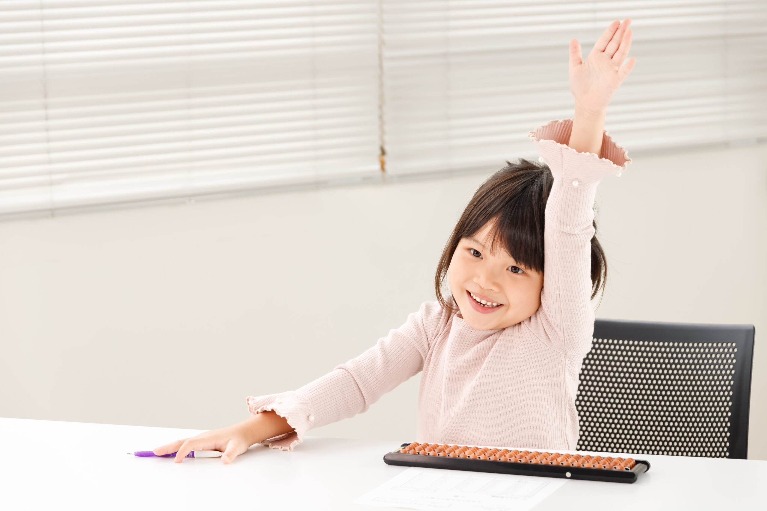 元気よく手を挙げる子どもとそろばん